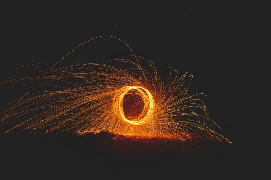 Emocje zapisane w ciele – Jak blokady energetyczne wpływają na Twoje decyzje? Captivating steel wool photography showcasing vibrant sparks and dynamic energy at night.
